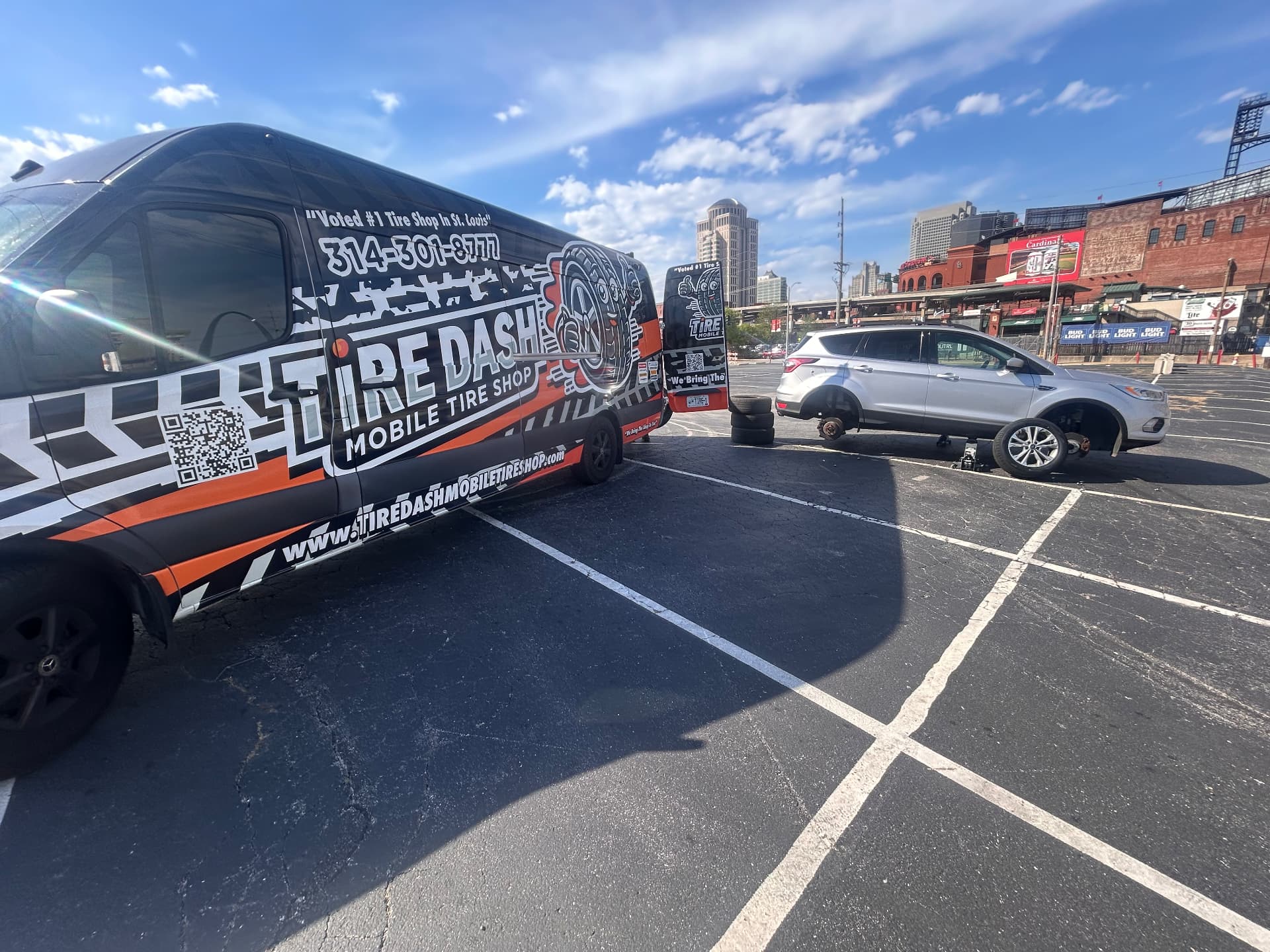 Tire Dash van beside a vehicle with a flat tire in a downtown parking lot